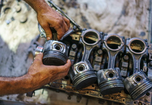 Close up view of hands working on a car engine in repair shop