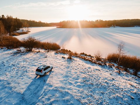 aerial view of the suv car at the beach of frozen lake on sunset copy space
