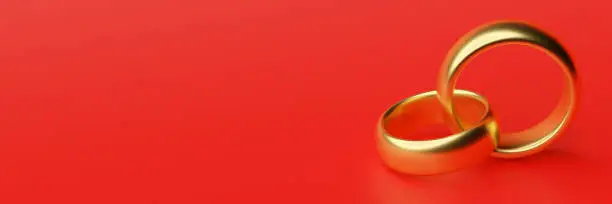 Banner of two wedding gold rings lie on each other with blank red space background. 3d rendering
