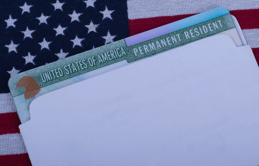 Green card or USA Permanent resident card on Flag of United States of America background. Free copy space. Close up view.
