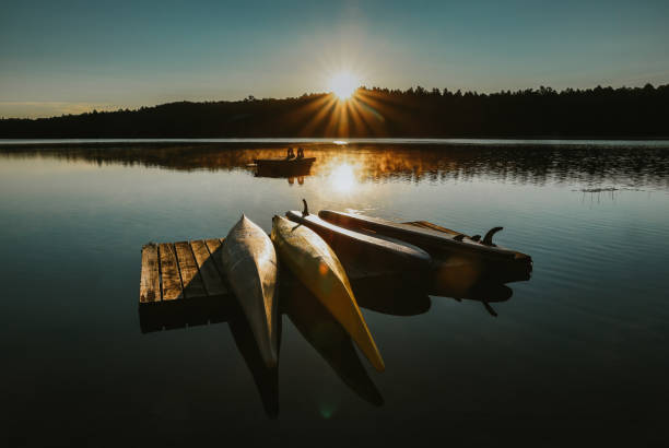 Kayaks and SUPs resting on a dock on a lake at sunrise. stock photo