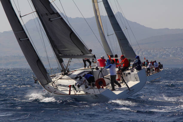 segelboote segeln bei windigem wetter im blauen wasser der ägäis - sailboat storm teamwork competition stock-fotos und bilder