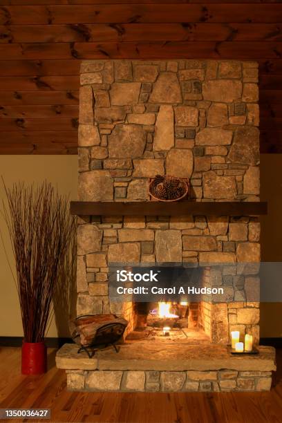 A Romantic Setting By A Stone Fireplace With Candles And Logs Burning In The Mountainside Cabin Stock Photo - Download Image Now