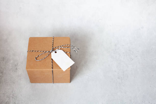 istock Craft gift box with a empty label and twine on a grey concrete background. 1350038322