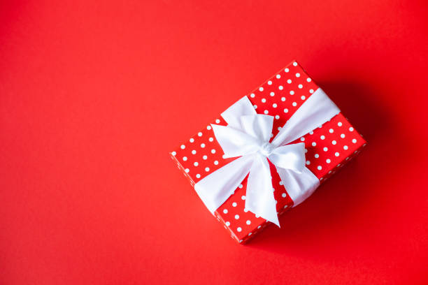 istock Red polka dots gift box with white bow on a red background. 1350038347