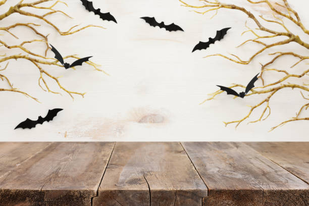 istock Halloween holiday concept. Empty rustic table in front of bare trees and bats background. Ready for product display montage 1350038376