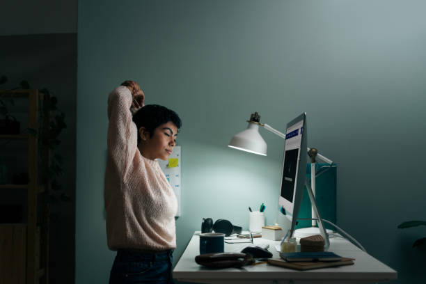 Young woman tired in front of computer late at night stock photo
