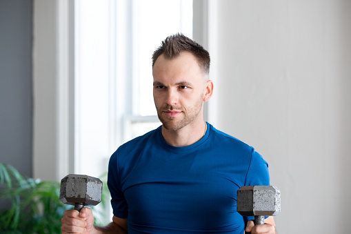 Muscular Man lifting weights at home