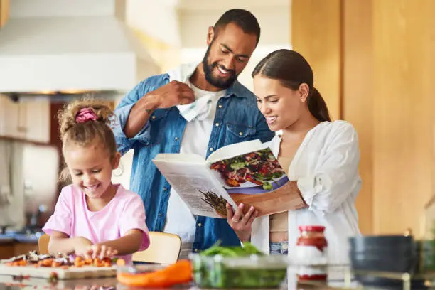 Photo of Shot of a couple and their daughter cooking together in the kitchen at home