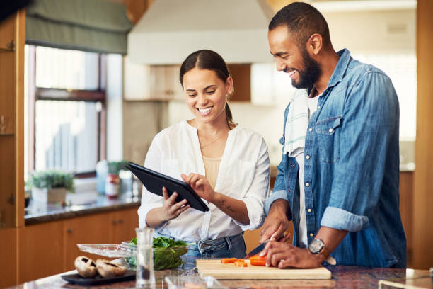 istock Shot of a young couple using a digital tablet while cooking at home 1350051818