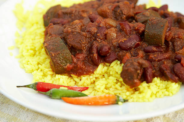 Cooked beans in tomato sauce served in a traditional clay bowl on a white background