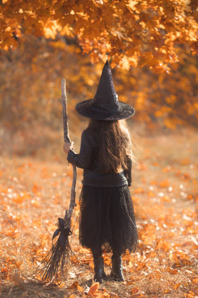 Faceless portrait of beautiful young girl with long brown hair from behind dressed as a witch with broom walking in fall forest Faceless portrait of beautiful young girl with long brown hair from behind dressed as a witch with broom walking in fall forest. High quality photo broom photos stock pictures, royalty-free photos & images