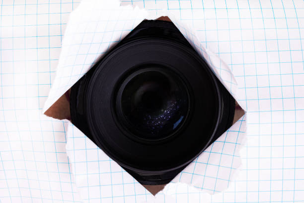 Camera lens in a torn hole in paper