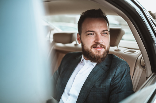 Happy Male Businessman Contemplating Business Opportunities While Traveling By Car
