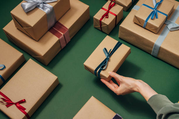 istock Anonymous Person Holding One of Many Gift Boxes on a Green Background 1350065480