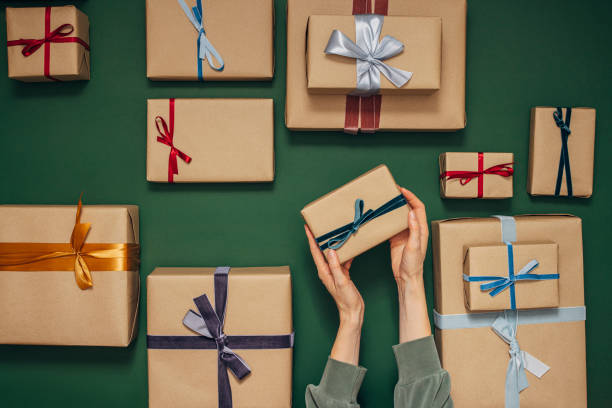 istock Anonymous Person Holding One of Many Gift Boxes on a Green Background 1350065488