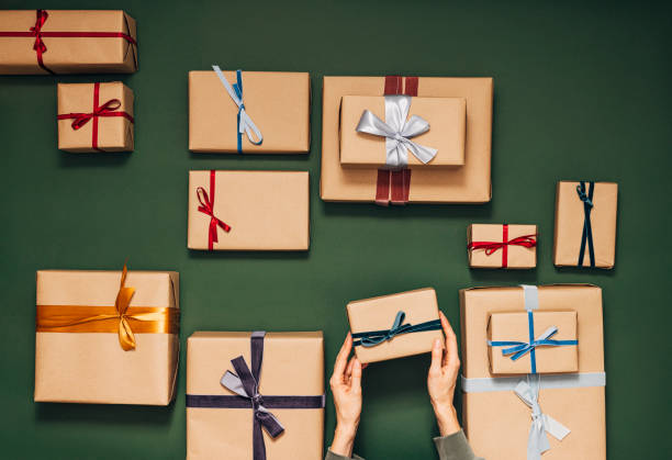 istock Anonymous Person Holding One of Many Gift Boxes on a Green Background 1350065489