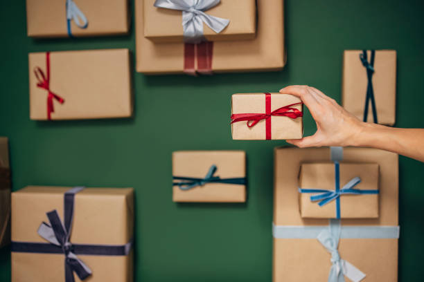 istock Anonymous Person Holding One of Many Gift Boxes on a Green Background 1350065492