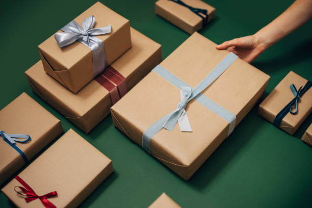 istock Anonymous Person Holding One of Many Gift Boxes on a Green Background 1350065499