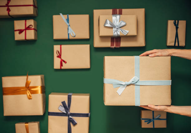 istock Anonymous Person Holding One of Many Gift Boxes on a Green Background 1350065503