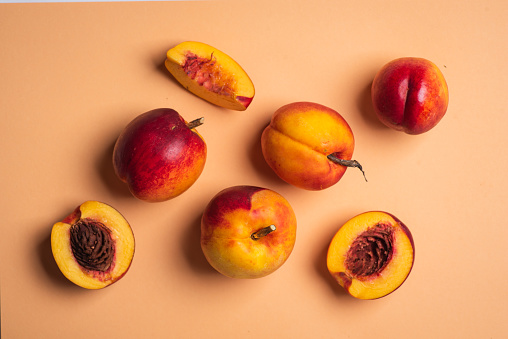 Ripe organic peaches on a light pink background. Top view