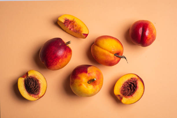 Ripe organic peaches on a light pink background. Top view stock photo