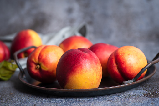 Fresh, organic, peach in a bowl on a gray-black background up close