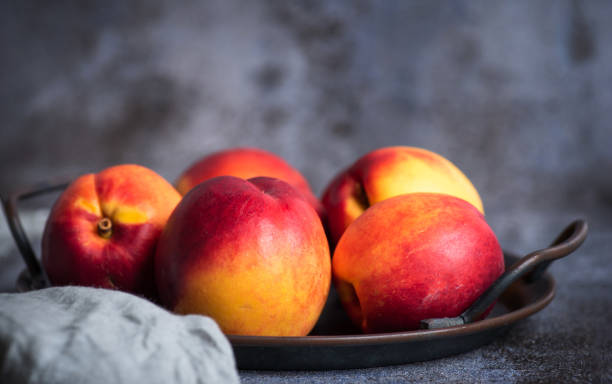 Fresh, organic, peach in a bowl on a gray-black background up close