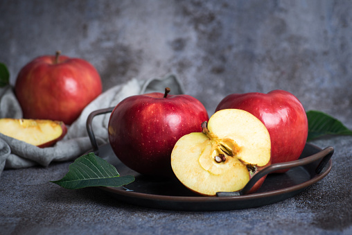 Fresh, organic, red apples in a bowl on a gray background, close up