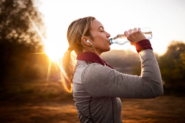 giovane donna in forma che si prende una pausa dal jogging nella natura durante l'alba - adult jogging running motivation foto e immagini stock