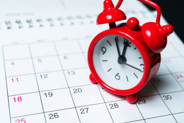 istock Classic clock stands on a paper calendar with a month by day 1350070909