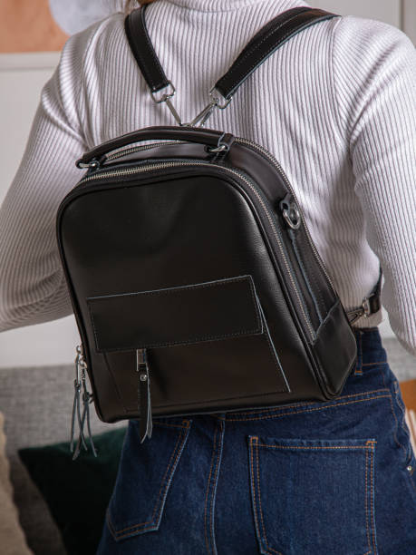 istock black backpack bag with straps on girl's back. bag for things, accessories and textbooks. Leather backpack with locks. 1350079014