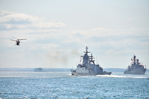 Battleships war ships corvette during naval exercises and helicopter maneuvering over water in Baltic Sea. Warships, helicopters and boats perform tasks in sea, military warships sailing, Russian Navy