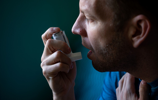 Young man using asthma inhaler