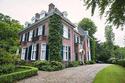 The Hague, Netherlands - june 12 2019 : the residence mansion of an ambassador with the flag of portugal, the entry way and ivy on the building.
