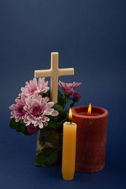 Composition of burning candle, flowers and wooden cross for all souls day. Also suitable for funeral, mourning, grief. Composition of burning candle, flowers and wooden cross for all souls day. Also suitable for funeral, mourning, grief. Vertical, high angle view. pink memorial candle with flowers stock pictures, royalty-free photos & images