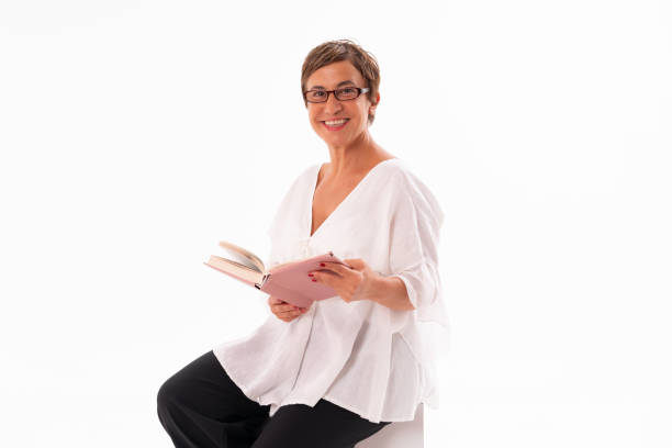 istock Mature woman holding book isolated on white. 1350092364