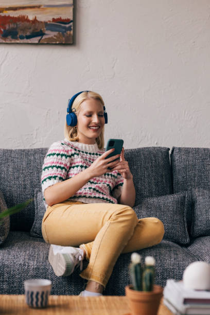 istock Young Woman with Headphones Using Mobile Phone at Home 1350092701