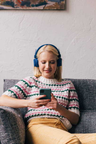 istock Young Woman with Headphones Using Mobile Phone at Home 1350092706