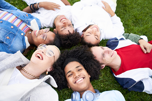 Group of friends laughing outdoors lying on the grass, sharing a good and positive mood. High quality photo