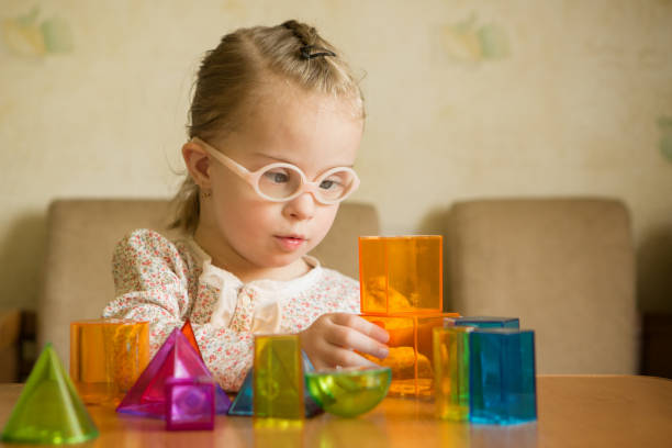 Girl with Down syndrome playing with geometrical shapes Girl with Down syndrome playing with geometrical shapes montessori stock pictures, royalty-free photos & images