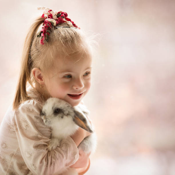 une fille atteinte du syndrome de down embrasse un lapin - pets table animal cheerful photos et images de collection