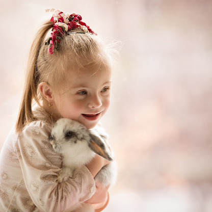 Girl with Down syndrome hugs rabbit