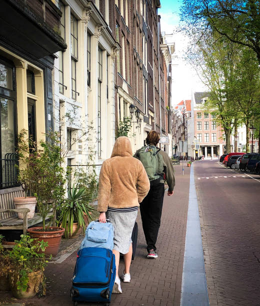 istock Amsterdam: Two Tourists with Luggage Walking Downtown 1350102501