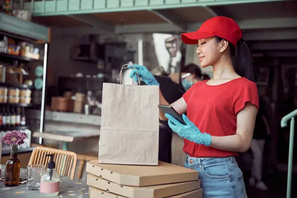 Photo of Asian employer working for food delivery service in cafe