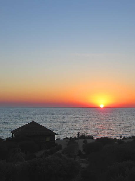 Sunset with a bungalow in the desert front of sea stock photo