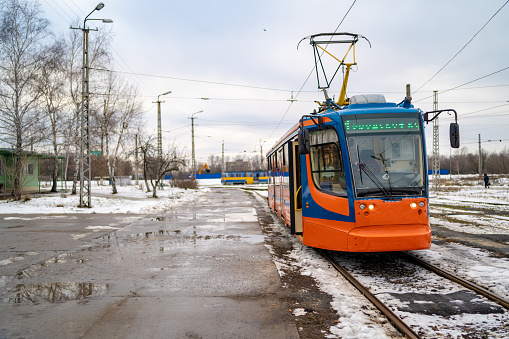 Modern tram in winter city. Contemporary tram is on tram station in cloudy day in countryside