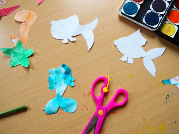 istock Desktop with drawing tools. A set of watercolor paints, pink scissors, pencil. View from above. Lesson or creative task 1350112873