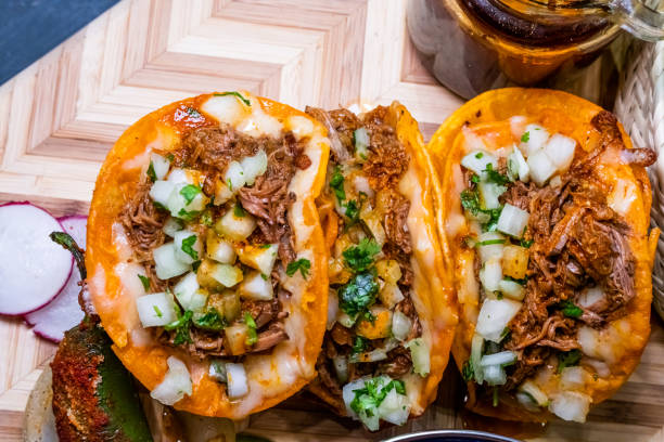 Authentic Gourmet Birria Tacos And A Bowl Of Delicious Mexican Consume, Soup, Arranged On A Wood Cutting Board stock photo