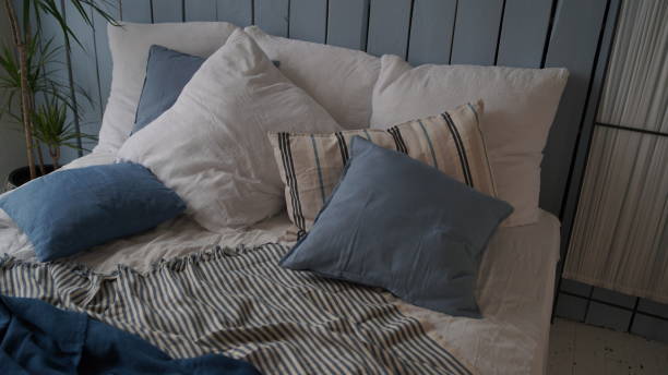 istock Large bed with pillows and blankets. Wooden stand for breakfast on crumpled bed in studio. Close-up of interior design room 1350116649